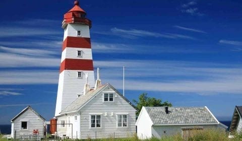 Il faro rosso e bianco di Alnes sotto un cielo azzurro