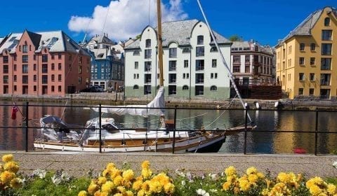 Zeilboot op het Brosund kanaal, kleurrijke Art Nouveau gebouwen langs het water, Ålesund