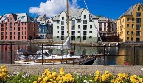 Zeilboot op het Brosund kanaal, kleurrijke Art Nouveau gebouwen langs het water, Ålesund