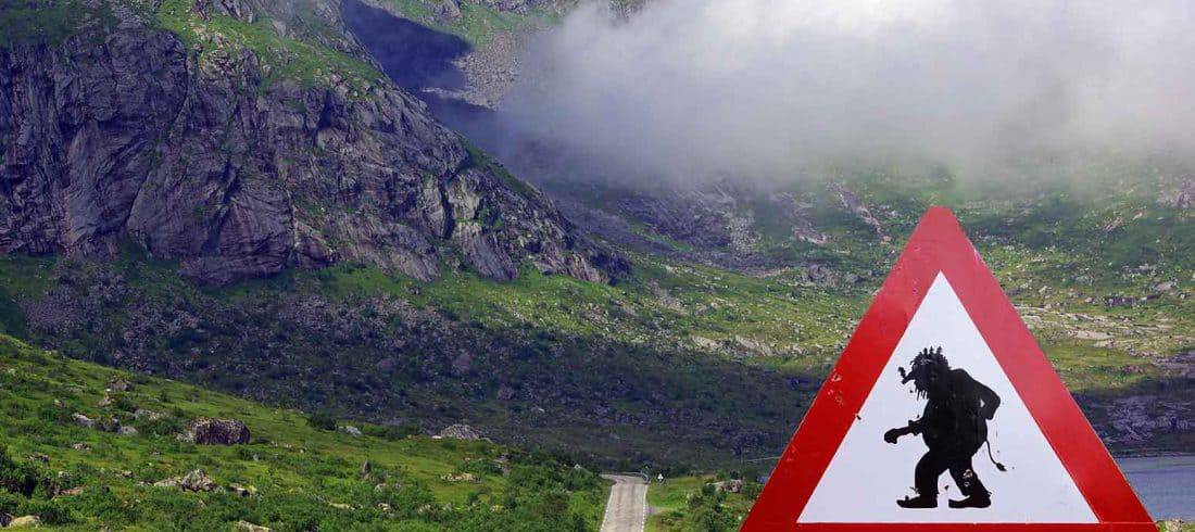 Sign warning for crossing Trolls in a green valley between Ålesund and Åndalsnes, Norway