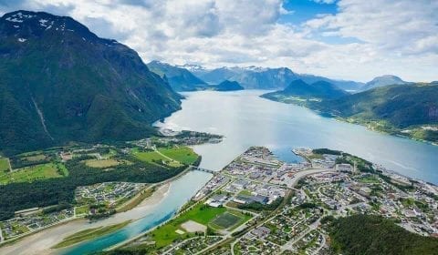 Panoramablick über die Stadt Åndalsnes, den hellblauen Rauma-Fluss und den Romsdalsfjord, umgeben von hohen Bergen