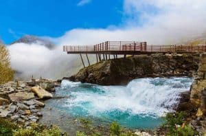 El agua fluye por el lado del mirador de Trollstigen, los mojones y las rocas por el lado