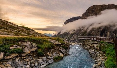 Klart vann strømmer på toppen av Trollstigen, utkikksplattform, skyer henger i dalen