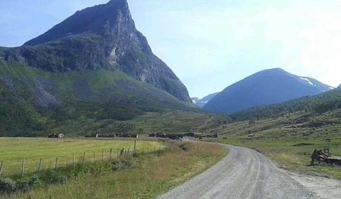 Mountain road leading to the traditional Goat Farm of Herdal, located between high green mountains