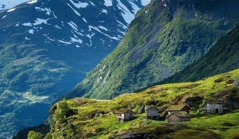 Trehytter med gresstak i de høye fjellene, snø på fjelltoppene