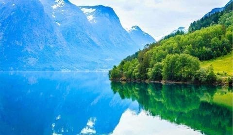 High mountains covered with green trees surrounding a mountain lake