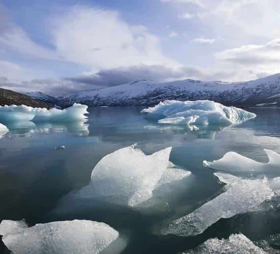 Kayakista en un lago glaciar, bloques de hielo flotando en el agua