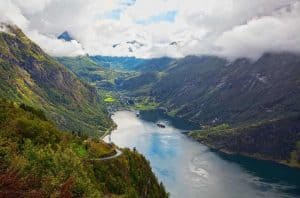 View from the Eagle Road, two cruise ships visiting the Geirangerfjord and Geiranger, mountains in the clouds