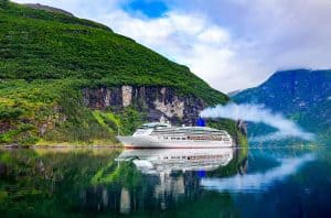 Cruise ship sailing over the Geirangerfjord with green mountains on the sides