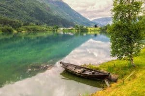 Verlaten houten boot aan de oever van een turquoise bergmeer buiten Olden