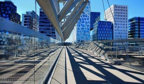 De Acrobaat, een voetgangersbrug over water, in de Streepjescode wijk in Oslo, moderne gebouwen in de achtergrond