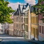 Ruhige Straße mit grünen Bäumen und bunten Jugendstilhäusern in der Innenstadt Ålesund, Norwegen