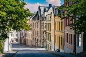 Ruhige Straße mit grünen Bäumen und bunten Jugendstilhäusern in der Innenstadt Ålesund, Norwegen