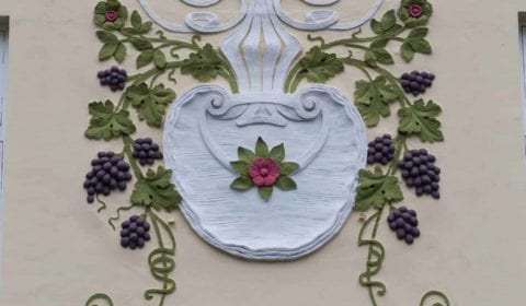 Ornamento Art Nouveau de un florero con uvas en la fachada de una casa en Ålesund, Noruega