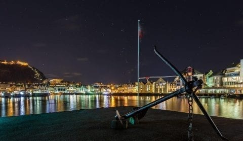 Ancla en un pequeño muelle en el centro de la ciudad de Ålesund bajo las estrellas al final de la tarde