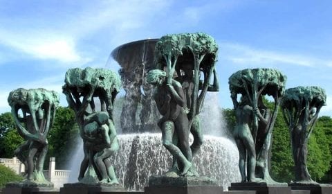 Skulpturer av menn og kvinner rundt en fontene på en klar dag i Vigelandsparken, Oslo, Norge