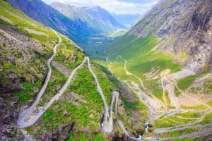 Utsikt over Trollstigen i en grønn dal omringet av høye fjell