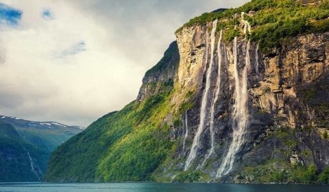 Chute des Sept Sœurs à Geiranger, Norvège Chute des Sept Sœurs plongeant dans le Geirangerfjord, montagnes vertes, ciel couvert