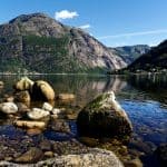 Felsen im klaren Wasser eines Fjords vor Eidfjord unter einem klaren blauen Himmel