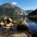 Steiner i klart fjordvann utenfor Eidfjord under en klarblå himmel