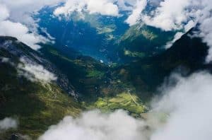 Montagne tra le nuvole, vista dal Monte Dalsnibba verso il fiordo di Geiranger, la valle verde e il villaggio di Geiranger