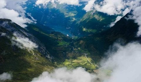 Fjell i skyene, utsikt fra Dalsnibba over Geirangerfjorden, den grønne dalen og bygda Geiranger