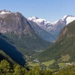 Vista aérea sobre el valle verde de Hjelle en el camino de Hellesylt a Geiranger, nieve en las cumbres de los montes a los lados del valle