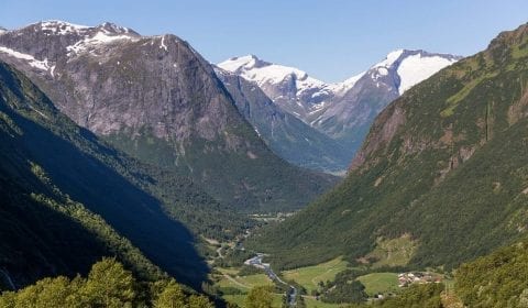 Luftfoto over den grønne Hjelledalen på veien fra Hellesylt til Geiranger, snø på fjelltoppene langs dalen