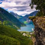 Panoramic view from the gorge of Flydalsjuvet over UNESCO's Geirangerfjord, few clouds hanging over the green mountains