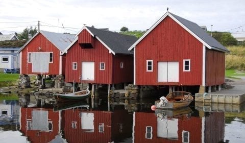 Casetas rojas y blancas de madera para barcos en la orilla del mar en el pueblo de Bud, cerca de Molde, Noruega