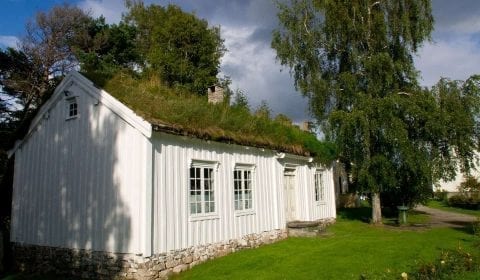 Weißes Holzhaus mit Grasdach und grünem Garten in Molde, Norwegen