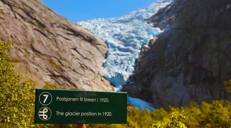 Schild mit dem Endpunkt des Gletschers 1920 mit dem aktuellen Briksdal-Gletscher, umgeben von Bergen im Hintergrund, Olden, Norwegen