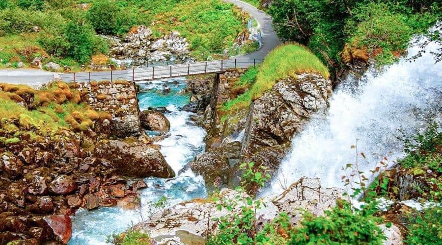 Frisches und klares blaues Wasser aus dem Wasserfall Kleivafossen, der unter einer Brücke in Olden, Norwegen, fließt