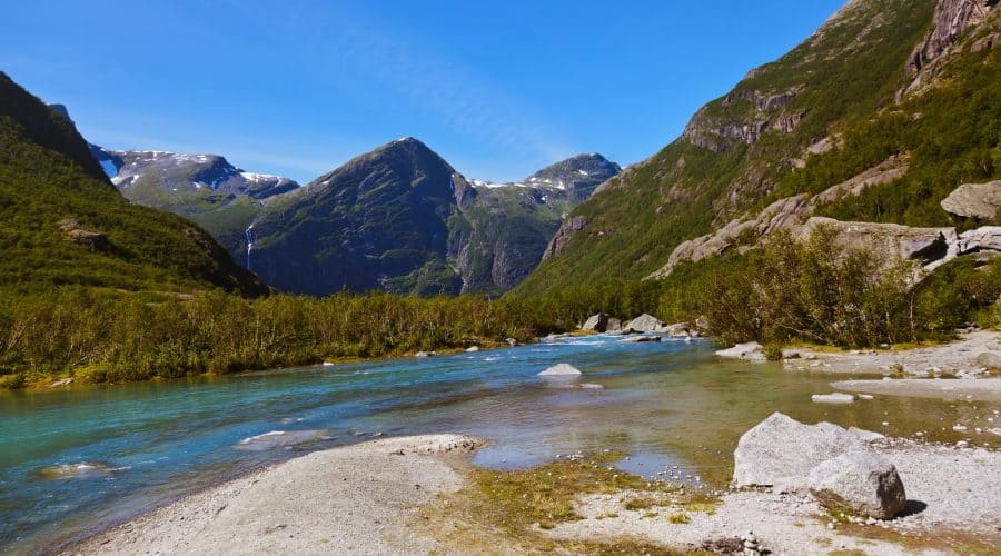 L'acqua blu e limpida dal ghiacciaio di Briksdal scorre tra le montagne verdi, Olden, Norvegia