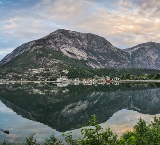 Rocas en el agua clara de un fiordo fuera del Eidfjord bajo un cielo azul claro