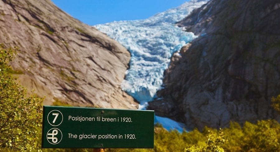 A trail marker on the hike to the Briksdal glacier with a view of the glacier in the background
