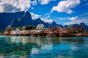 Rorbu cabins over crystal blue waters in Lofoten, Norway with dramatic mountains in the background