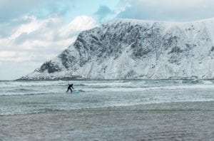 A surfer surfs in the waters of Lofoten, Norway