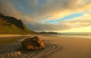 A view of the midnight sun over a sandy beach in , Lofoten, Norway.