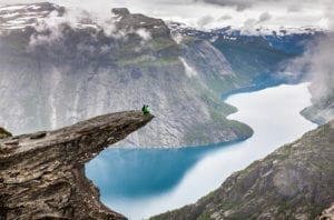 Hikers sitting atop Trolltunga in Norway.