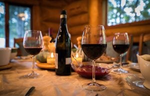 A cozy dining table set with wine and food inside a cabin.