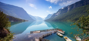 A view of row boats docked on the side of Lovatnet, a beautiful turquoise-blue lake in Norway.